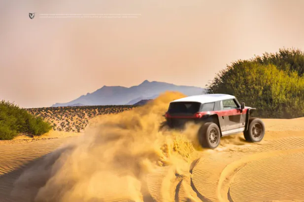 A Vanderhall Brawley throwing sand while driving across desert dunes